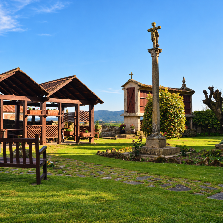 Jardín rural con cruz de piedra y hórreo